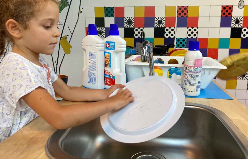 Una bambina gioca a lavare i piatti