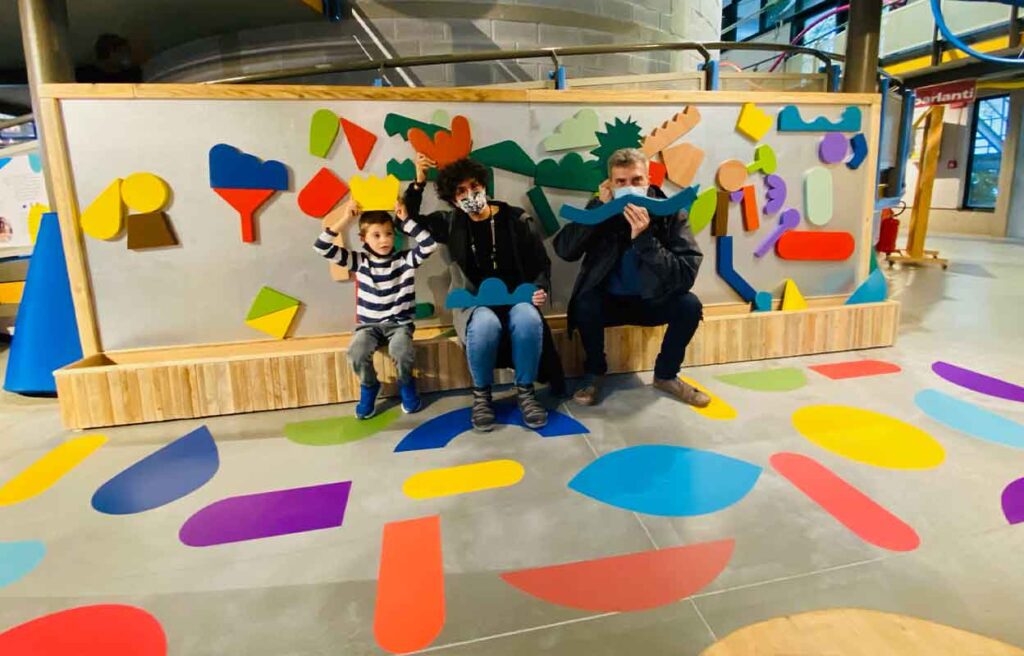 Una famiglia davanti alla parete magnetca di forme colorate 