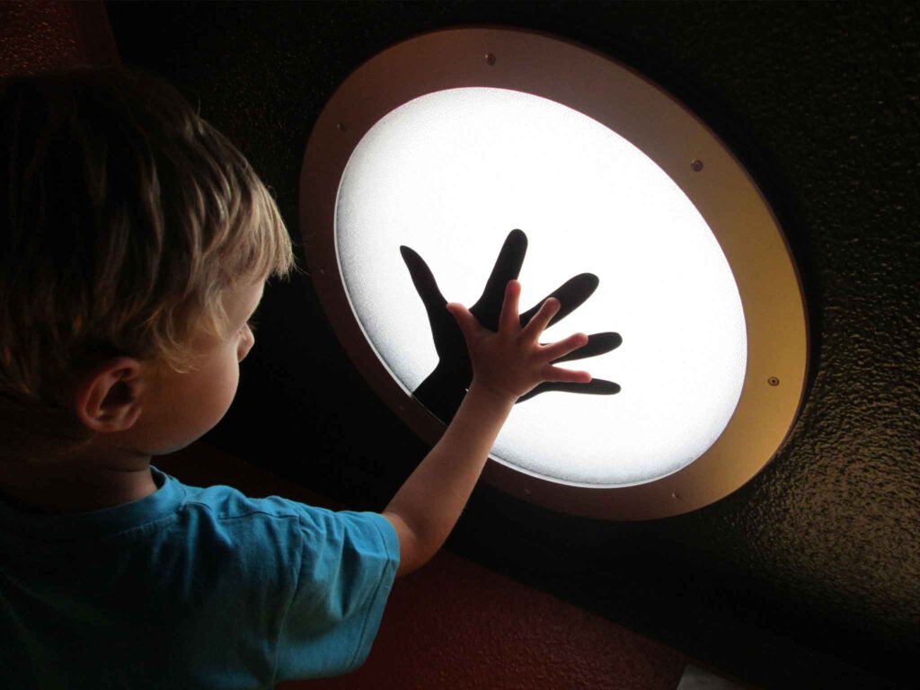 Bambino che preme la mano su un'installazione luminosa