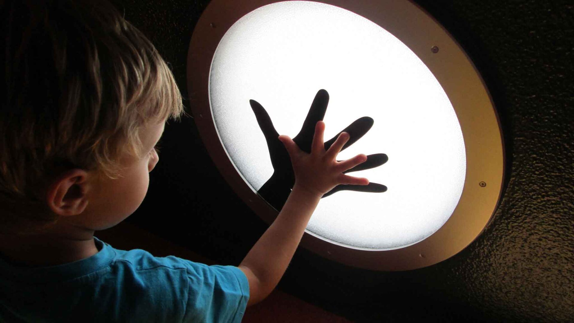 Bambino tocca con la mano una luce sensibile