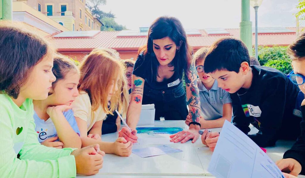 Artista realizza un workshop con bambini nell'area esterna del museo Explora