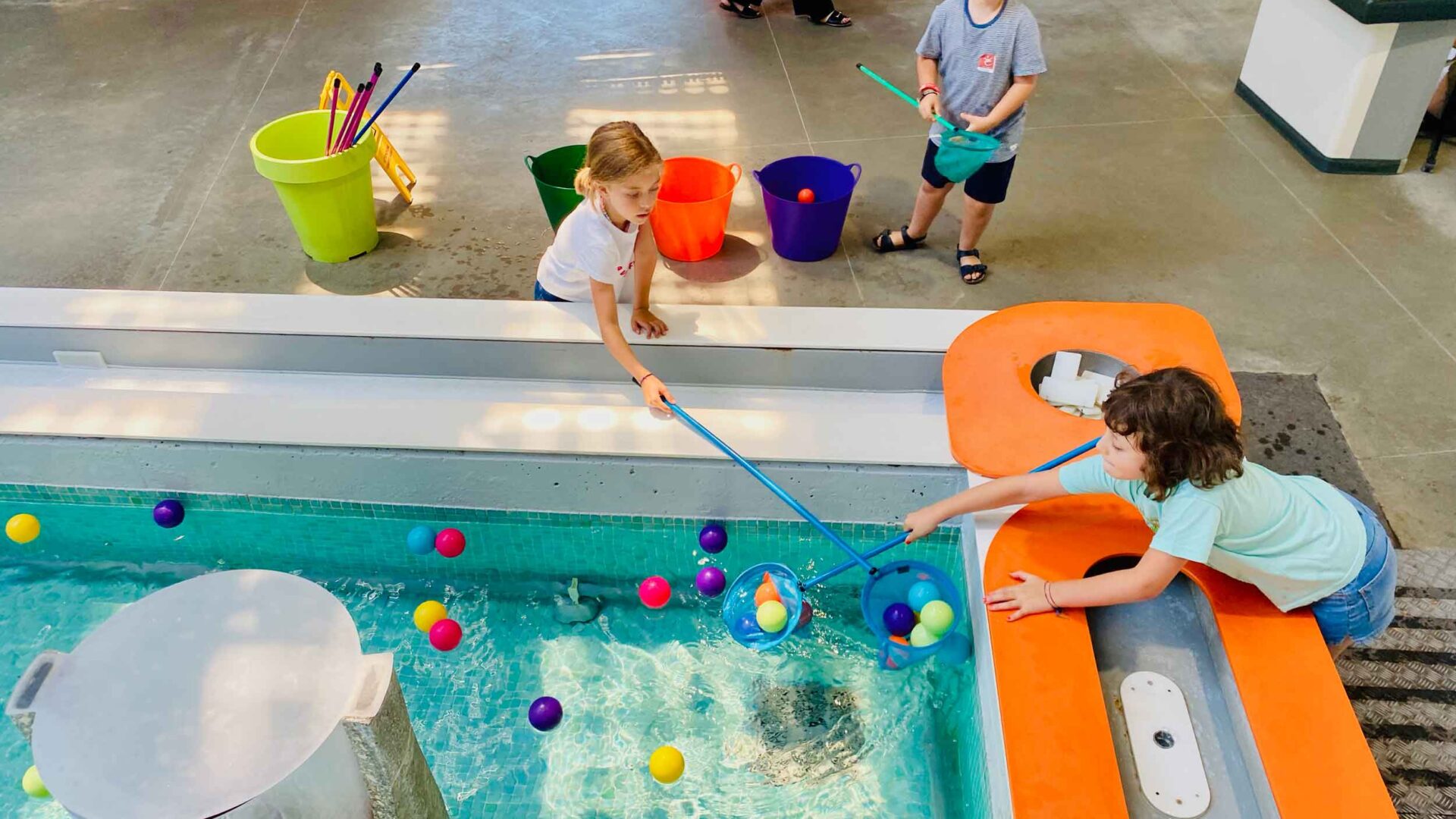 La fontana del museo Explora con bambini che giocano in estate raccogliendo le palline in plastica con dei retini da pesca