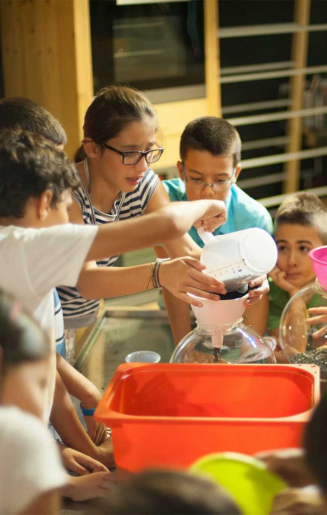 Bambini filtrano l'acqua attraverso un filtro naturale durante il laboratorio dedicato al ciclo dell'acqua