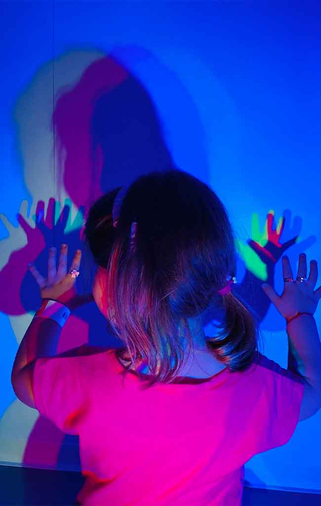 Bambina gioca con le ombre colorate presso Explora