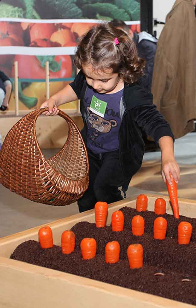Una bambina gioca con ortaggi finti