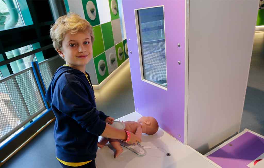 Un bambino prova ad allacciare il pannolino ad un neonato nel gioco dedicato alle pari opportunità