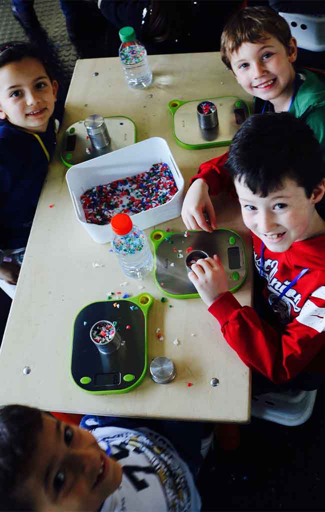 Bambini partecipano al laboratorio plastica preziosa pesando i fiocchi di plastica tritata