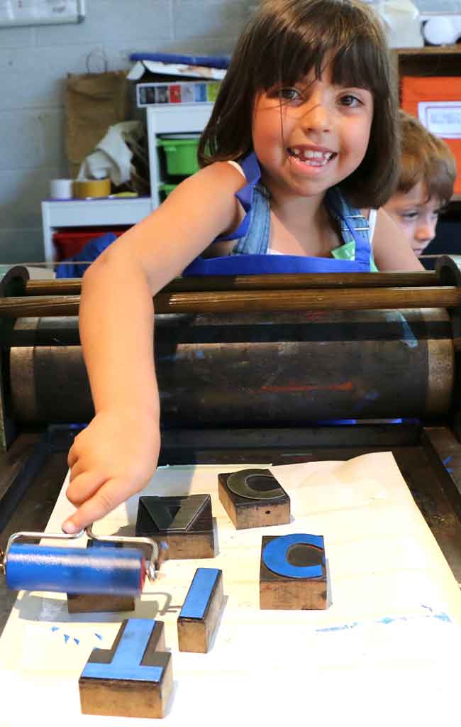 Bambina partecipa al laboratorio sulla tipografia colorando caratteri mobili
