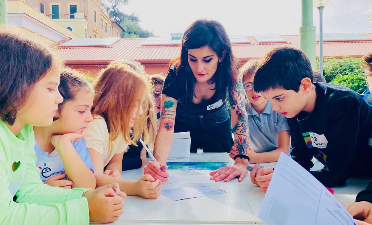 Un'artista realizza un workshop con i bambini nell'area esterna del museo Explora