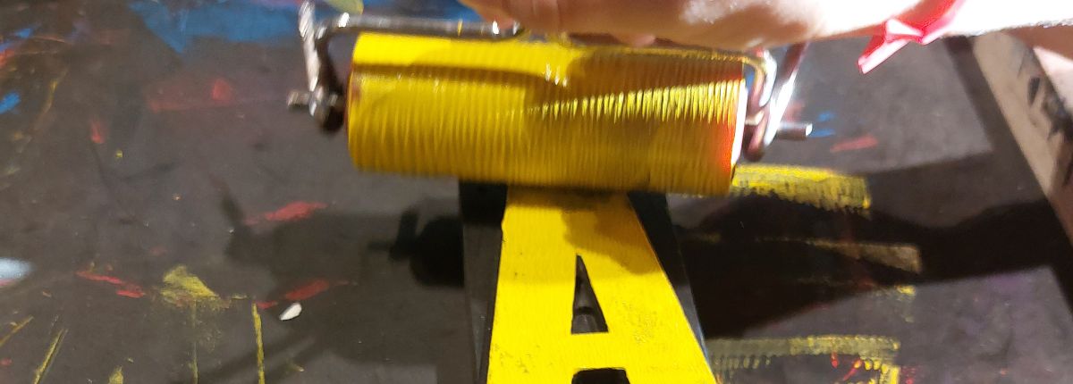 Un rullo passa la vernice gialla sulla lettera A di un carattere mobile