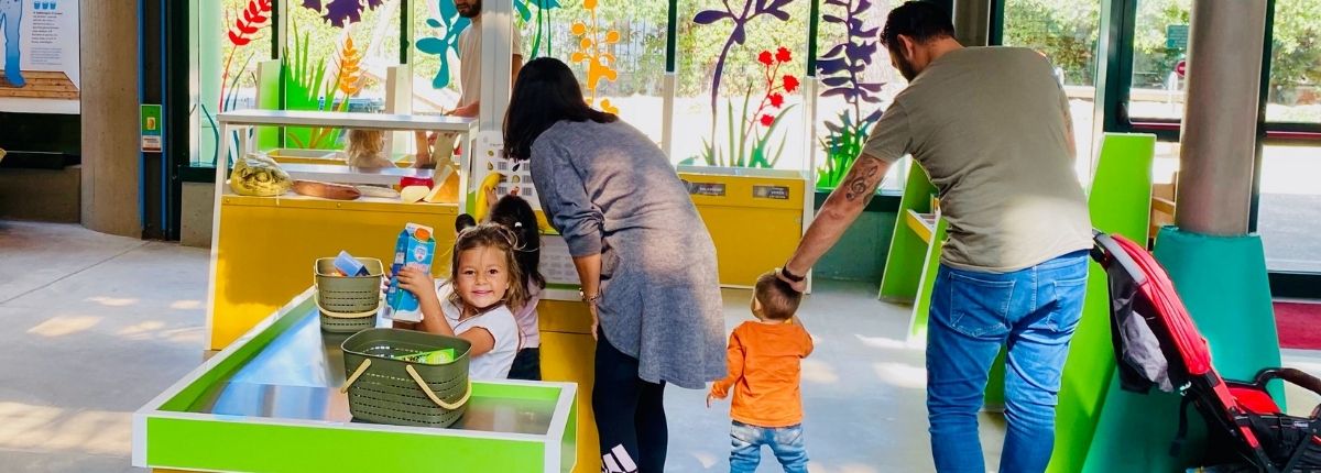 bambina gioca al supermercato di Explora insieme a bambini e adulti.
